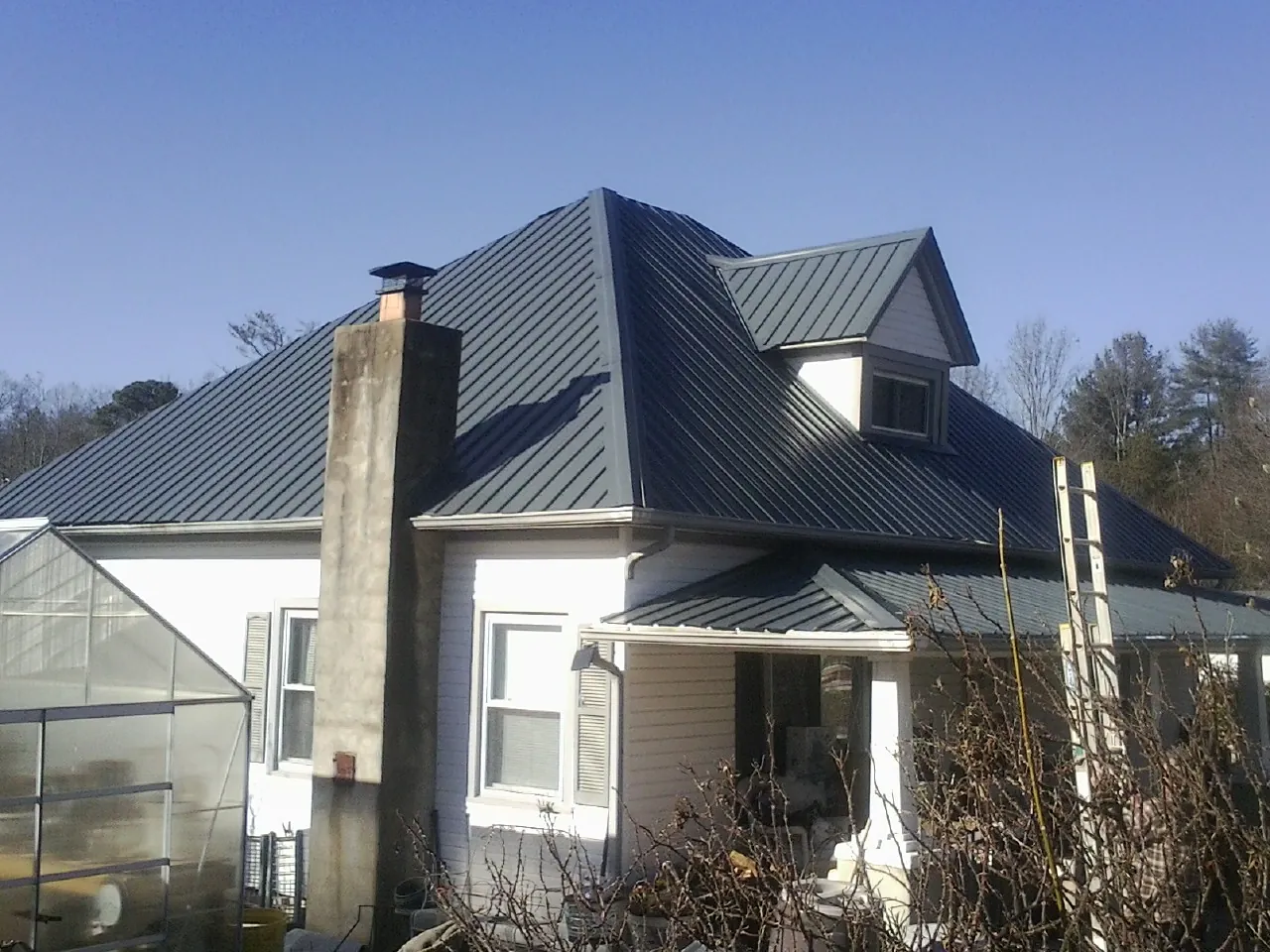 Dark blue standing seam metal roof on a white farmhouse with dormer — Slate & Tile Roof Repair by Roofing Brothers in Elberfeld