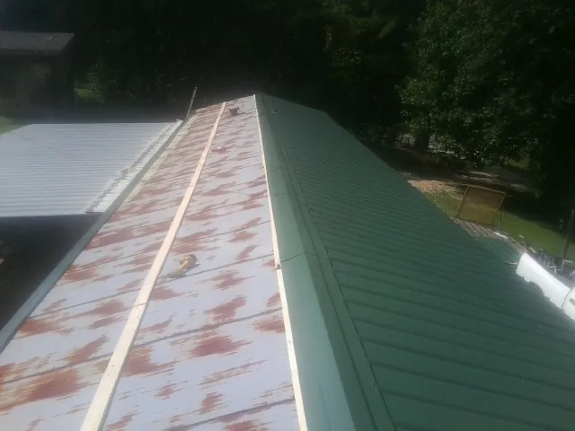 Old rusted panels beside newly installed green metal roofing — Wind Damage Roof Repair by Roofing Brothers in Elberfeld
