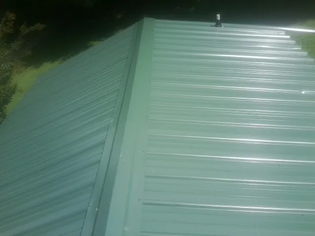 New green metal panels meeting at the ridge of a roof — Flat Roof Repair work by our crew in Elberfeld