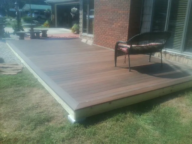 New wood deck and wicker chair beside a brick house in Elberfeld