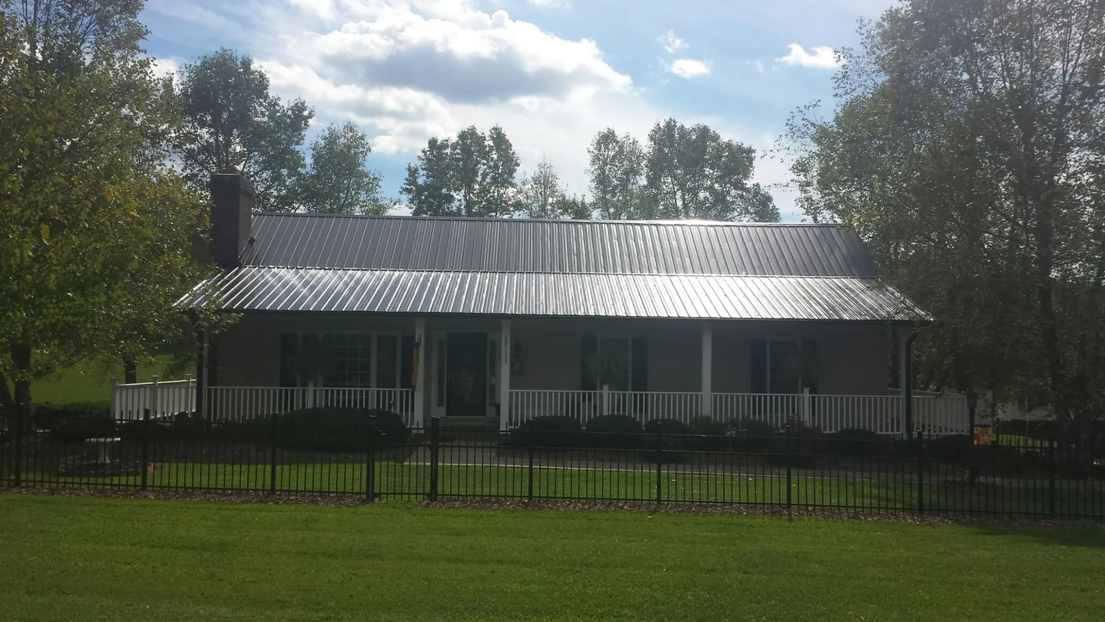 Gray metal roof on a brick ranch with a full width front porch — Gutter Guard Installation work by our crew in Elberfeld