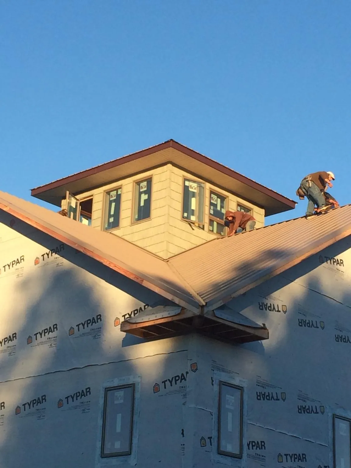 Roofers working around a rooftop cupola on a new metal roof at sunset — Roof Waterproofing in Elberfeld by Roofing Brothers